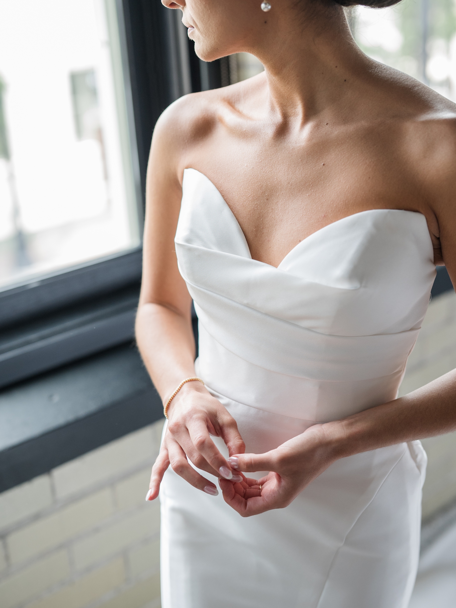 Bride in a strapless gown holding a white bouquet at Bottleworks Hotel.