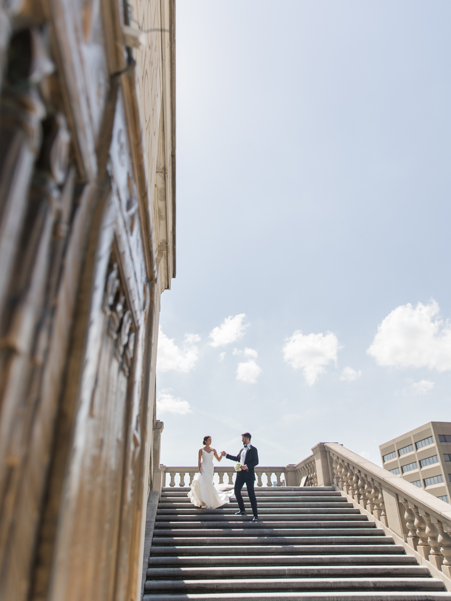 Black tie bride and groom embracing on stone steps in downtown Indianapolis.