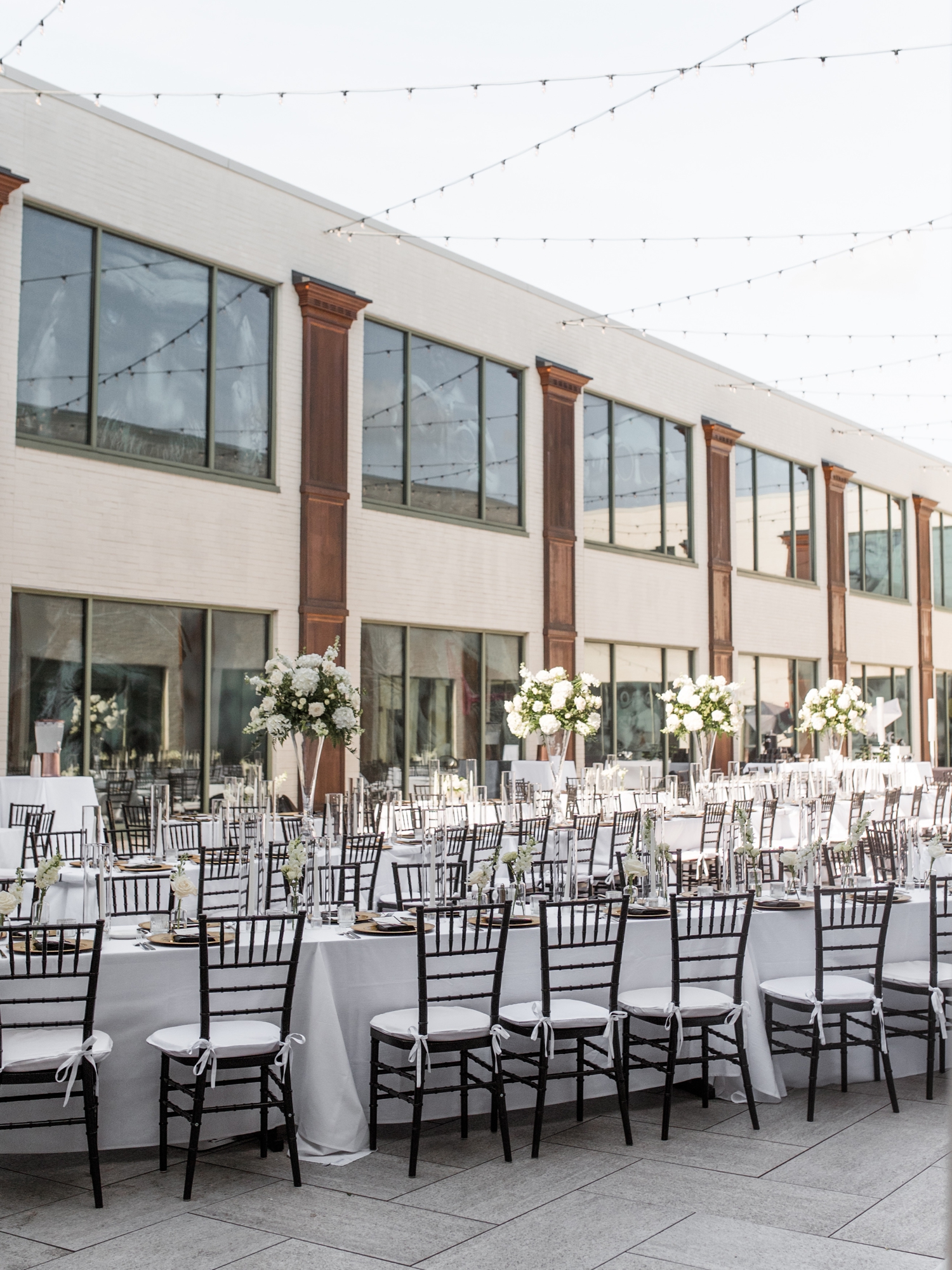 Al fresco reception setup at Bottleworks Hotel with white florals and candlelight.