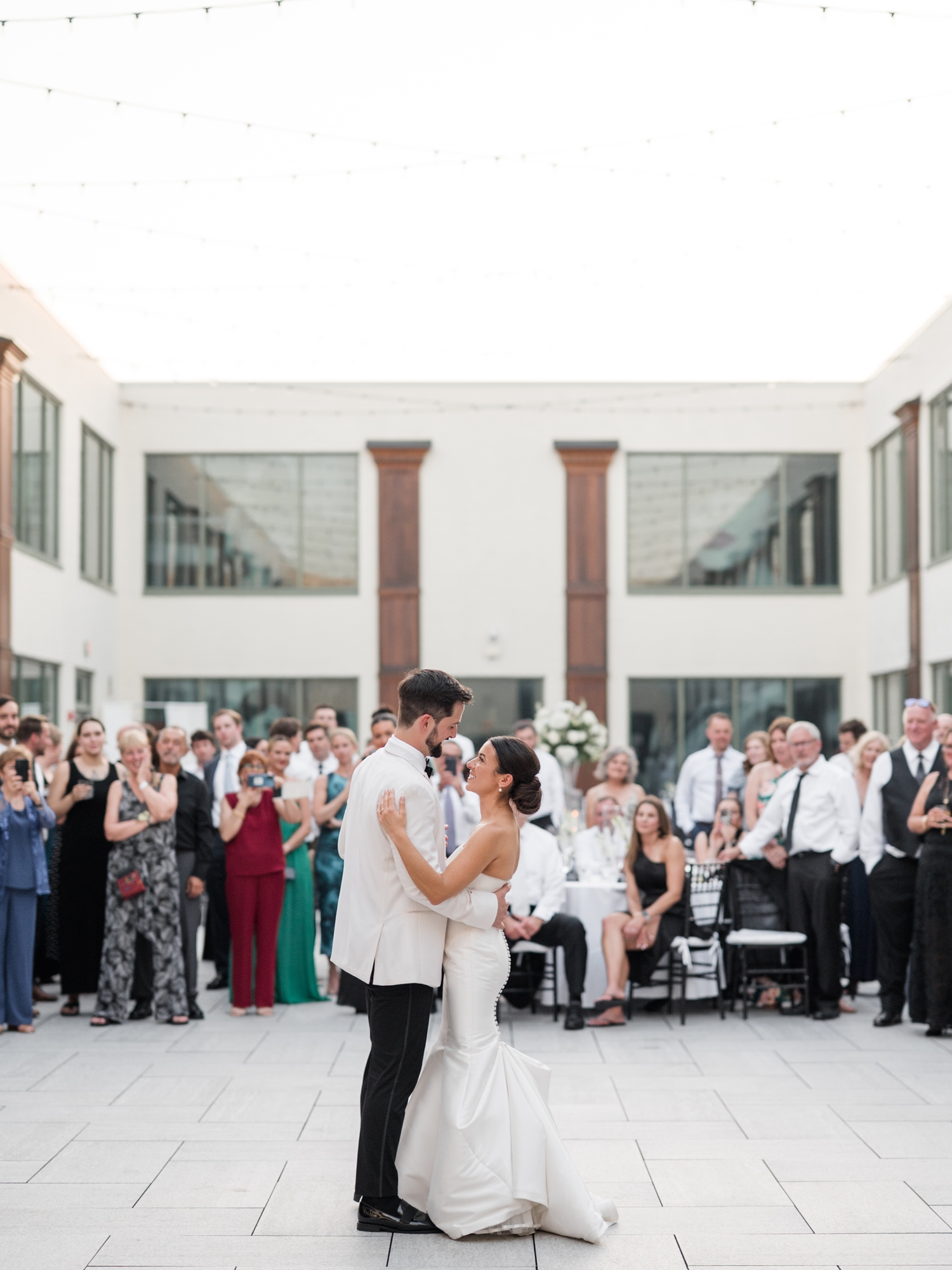 Outdoor first dance under string lights at a Bottleworks Hotel wedding.