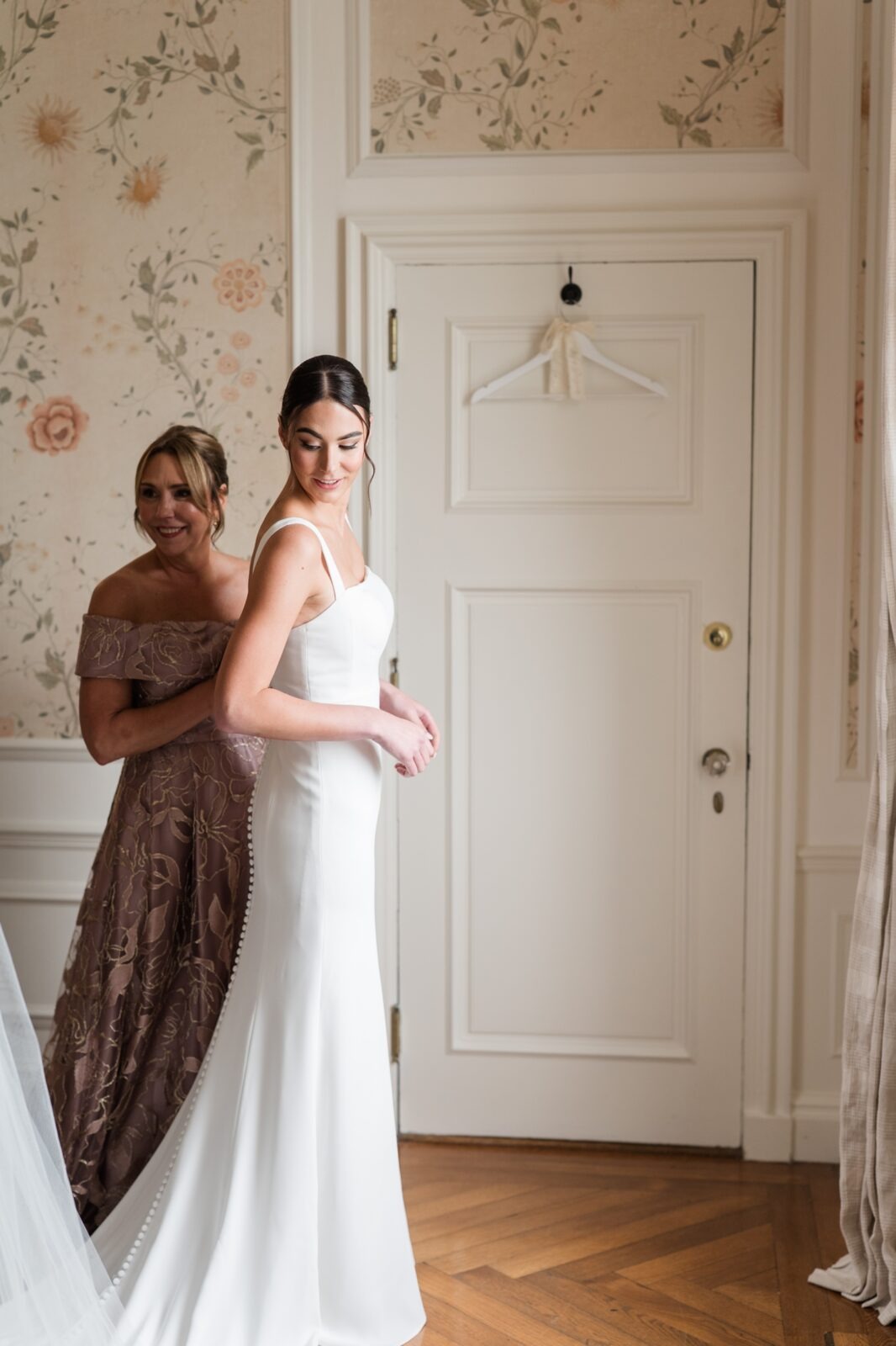 Bride smiling as her mother helps with her wedding gown inside the Alger House